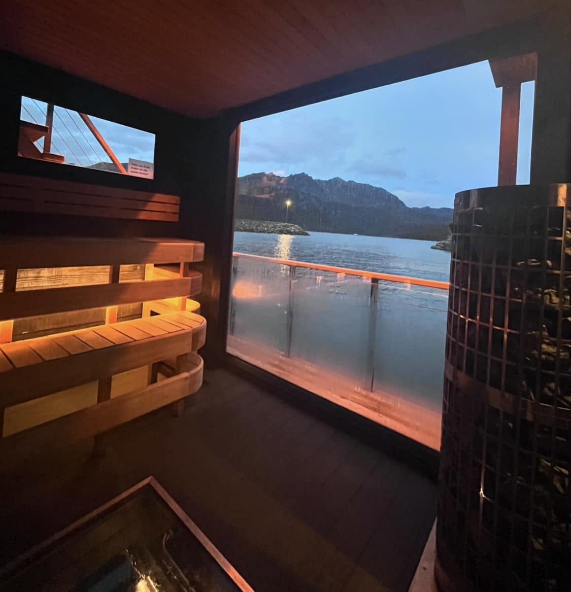 Floating sauna at night, lit up on the dark harbour