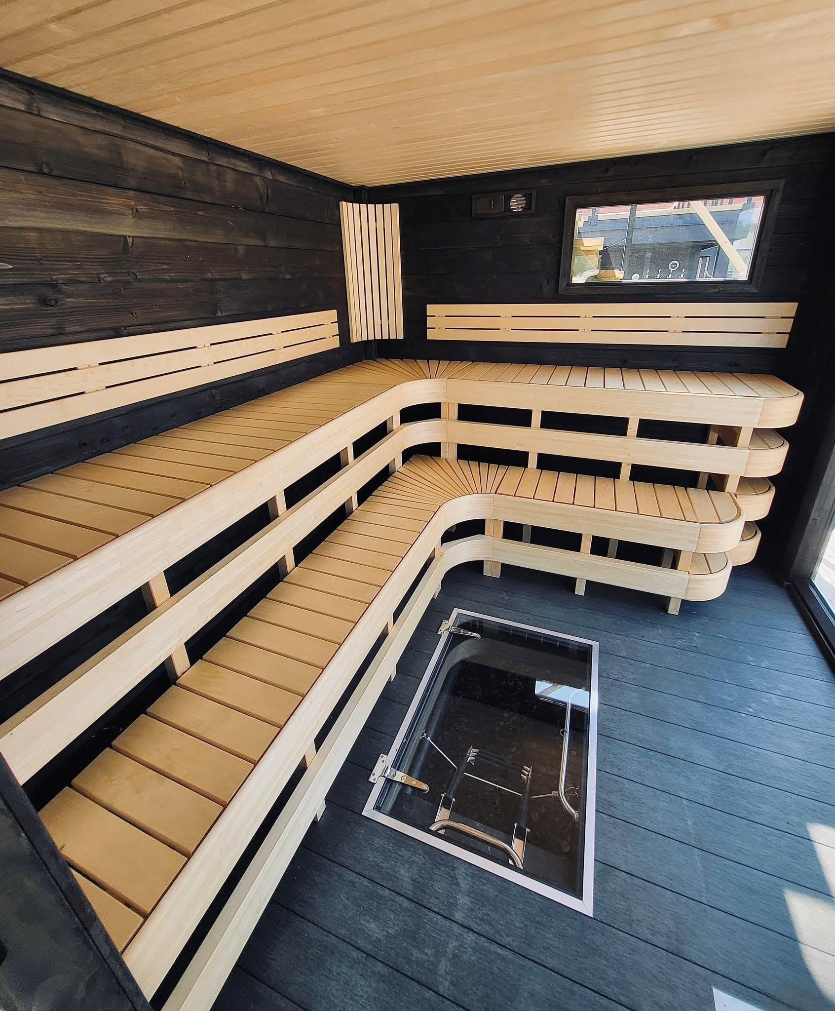 Curved wooden sauna benches with a glass-floor plunge pool, Damperiet interior in Fjordgård
