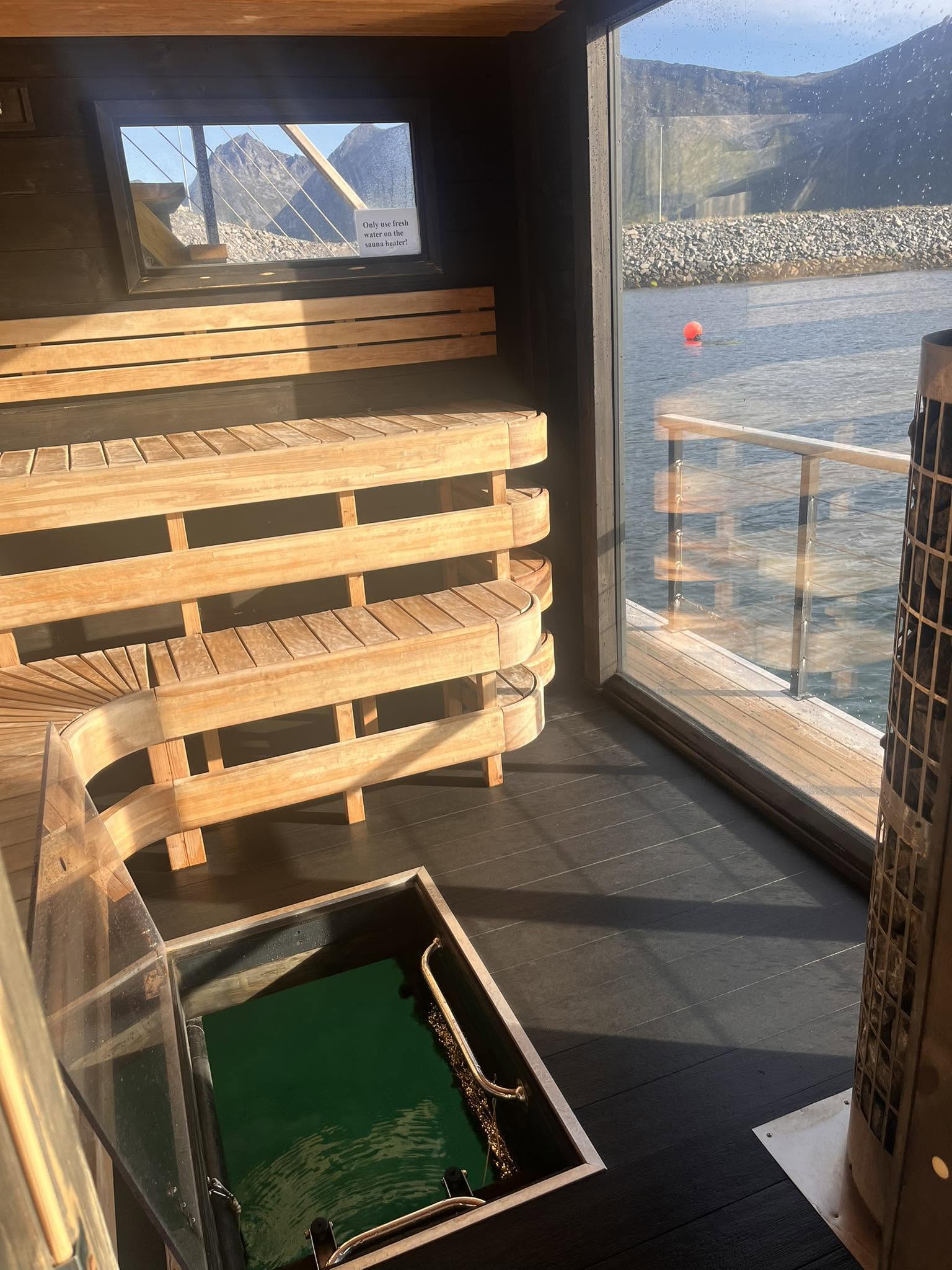 Sauna interior with mountain view through the window and a glass-floor plunge pool