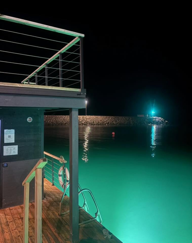 Sauna deck at night with glowing water
